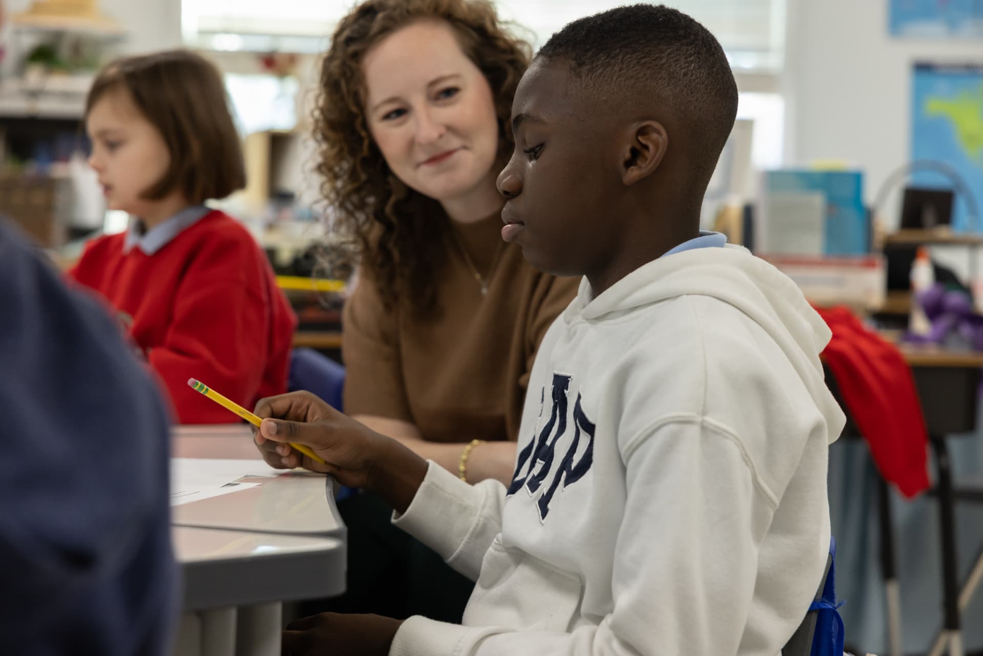 A teacher sitting beside a student and encouraging him through his work
