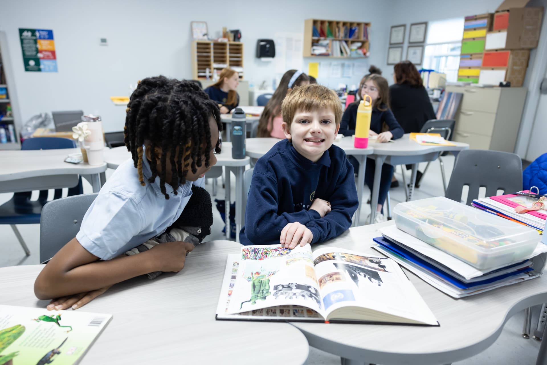 Two students smiling while flipping through a yearbook together