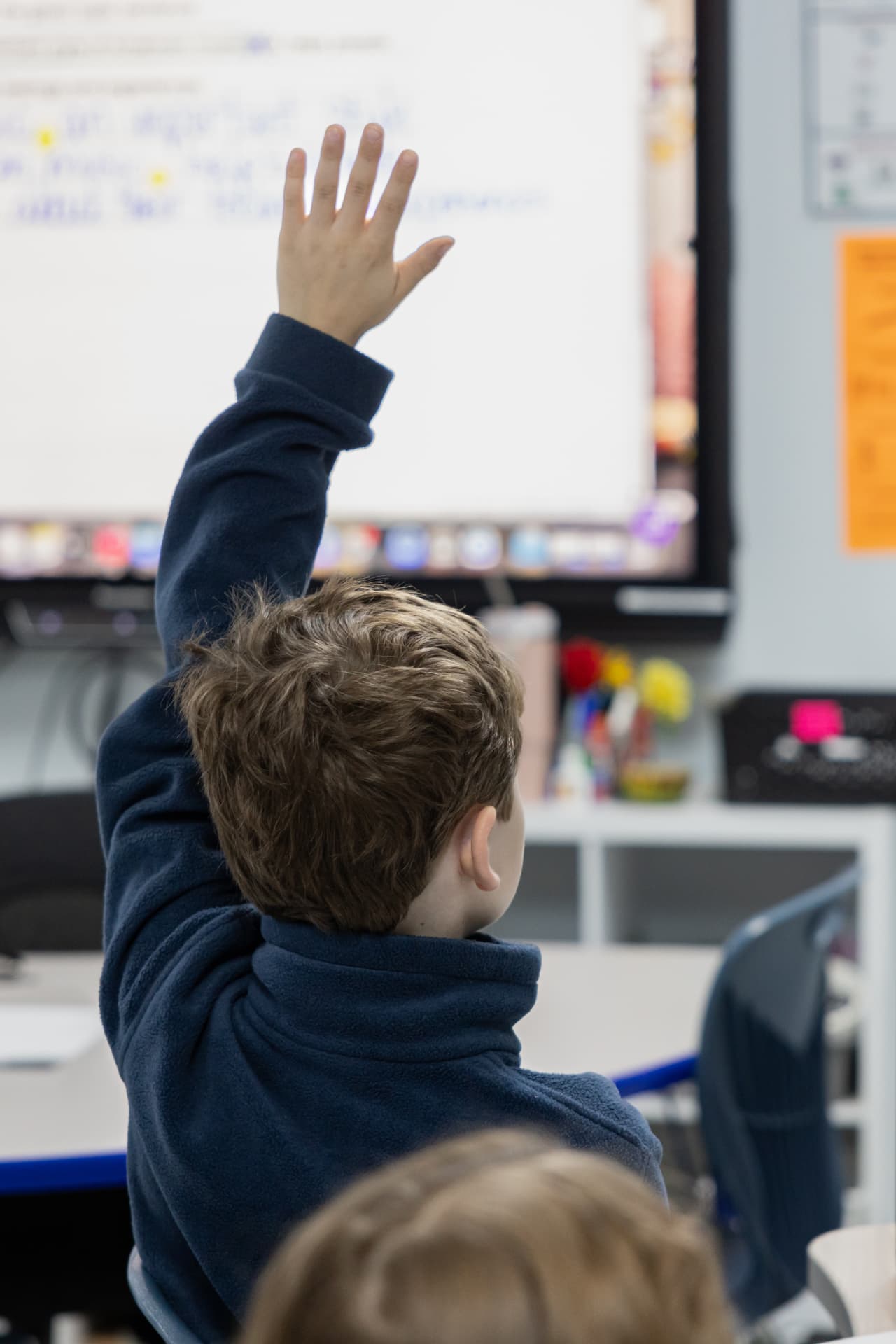 A Lighthouse Academy student raising his hand during a lesson at the classroom whiteboard